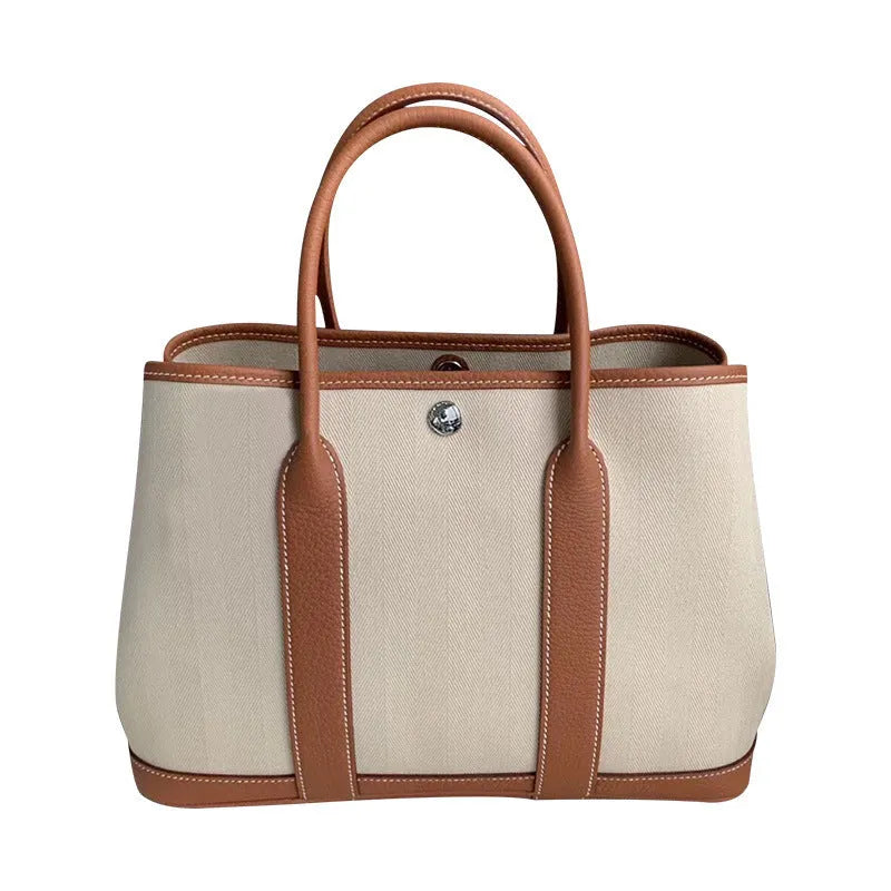 Women's canvas bucket tote bag with genuine leather trim showing open top and crossbody strap