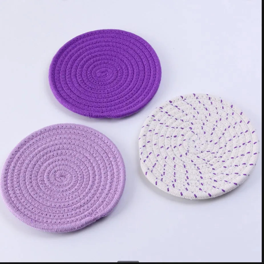 Three round blue cotton cord coaster placemats on a wooden table.
