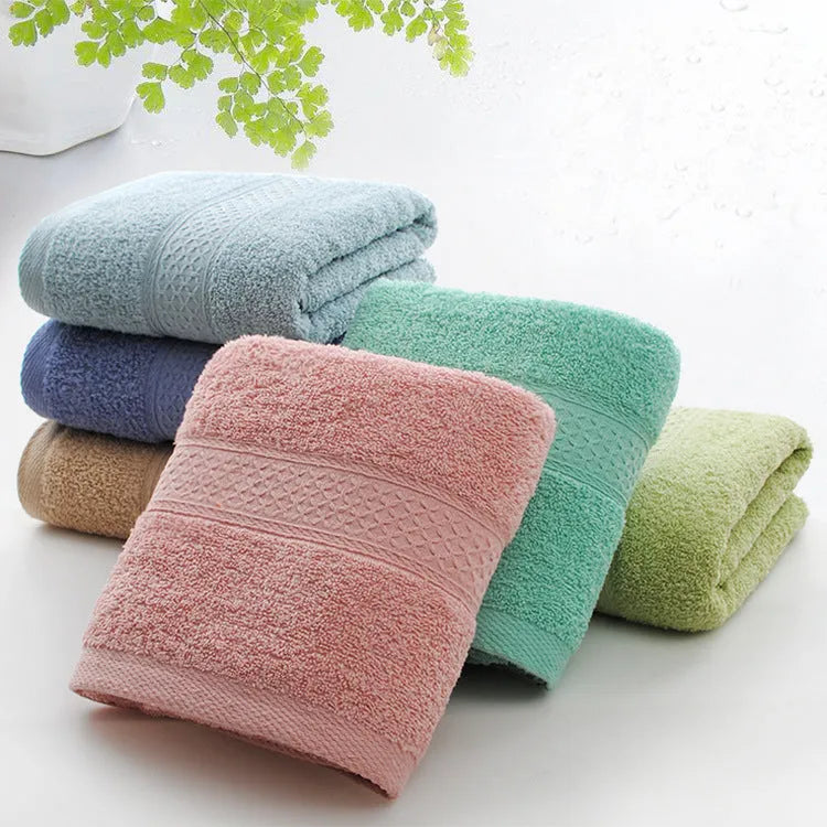 A pile of thickened cotton bath towels in various colours including apple green, dark blue, and light pink.