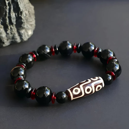 Close-up of a hand-woven black agate dzi bead bracelet with 11mm geometric beads on a wrist.