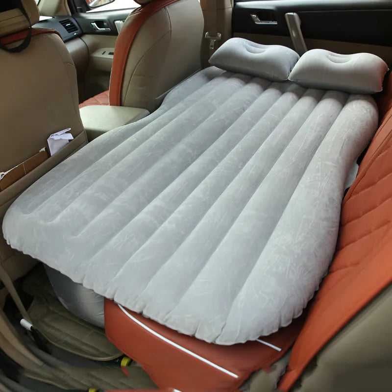 Black inflatable car bed with flocked surface and pillows set up in a car's back seats