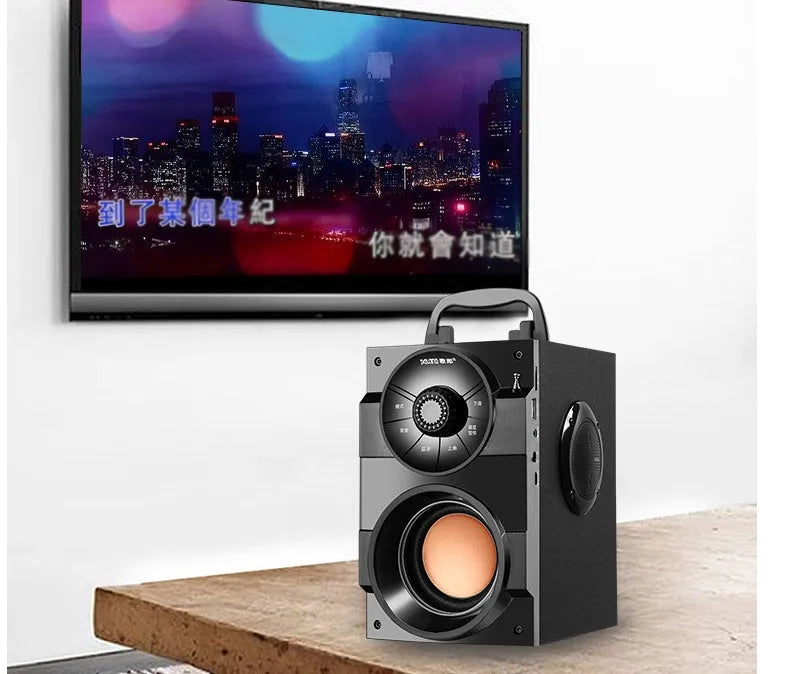 Black portable mini home audio system with subwoofer, satellite speakers, and USB charging cable on a desk.