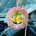 Hand-woven wool bell orchid car pendant in green, hanging from a car mirror.