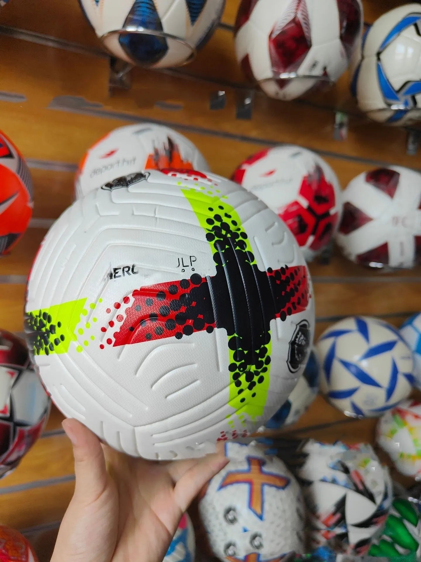 Fluorescent green official Size 5 football with seamless thermal adhesive patch PU construction on a training pitch.