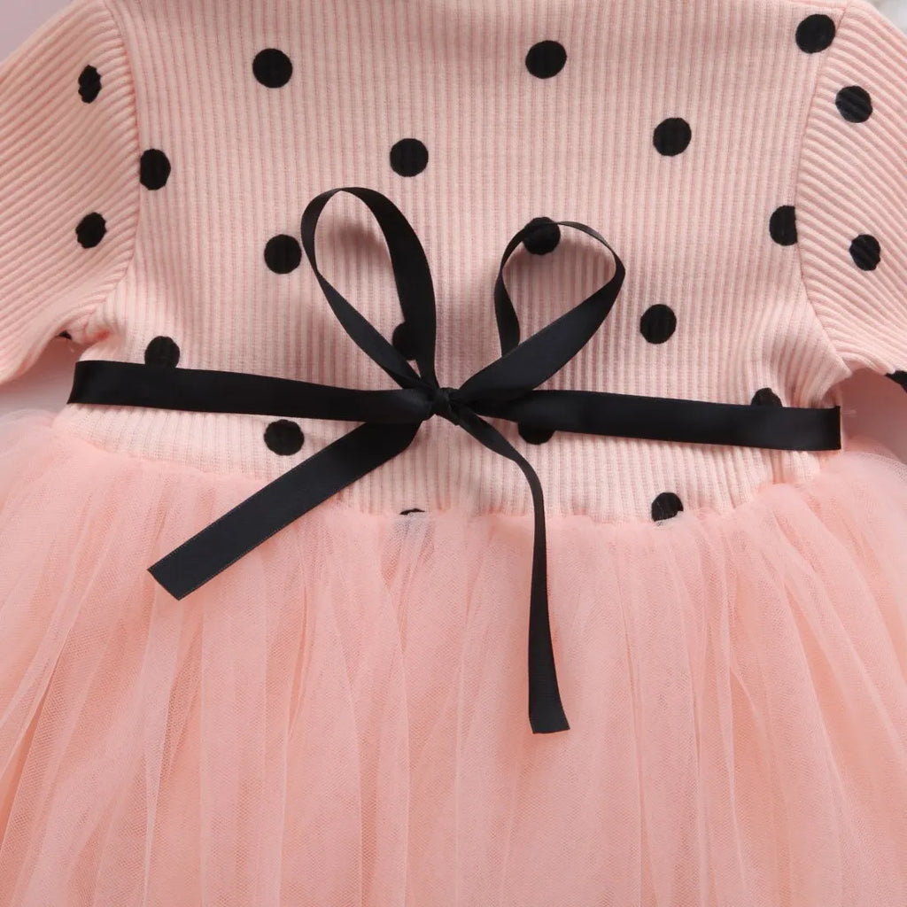 Baby girl wearing long sleeve lace tutu dress in pink, suitable for first birthday or christening events