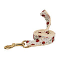 Red cherry printed cloth dog collar set with light gold buckle, matching leash, bow, vest, and bag.