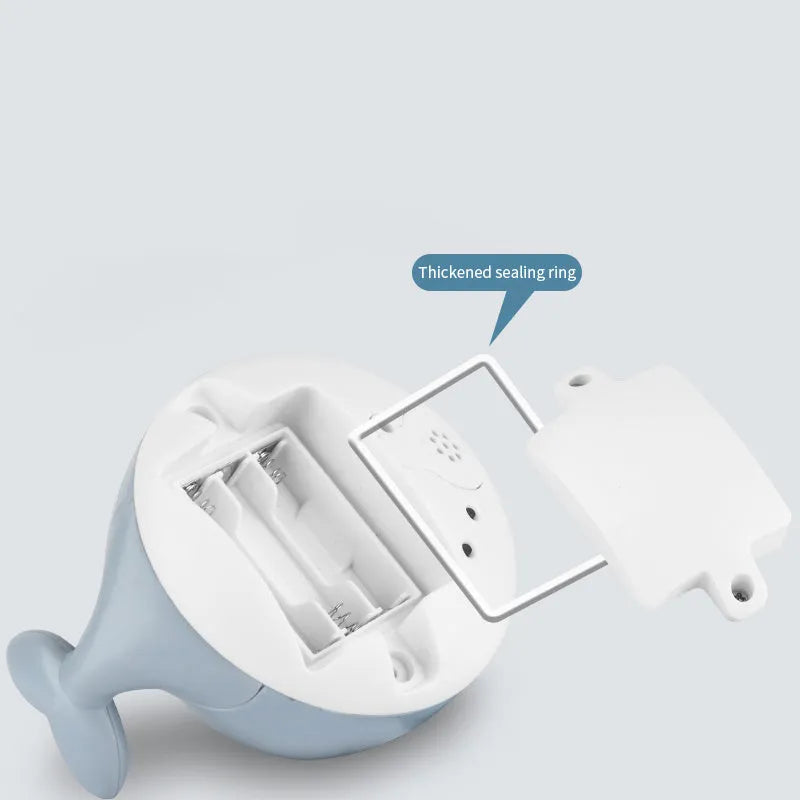 White and blue automatic whale bath toy spraying water with LED lights on, placed in a baby bath.