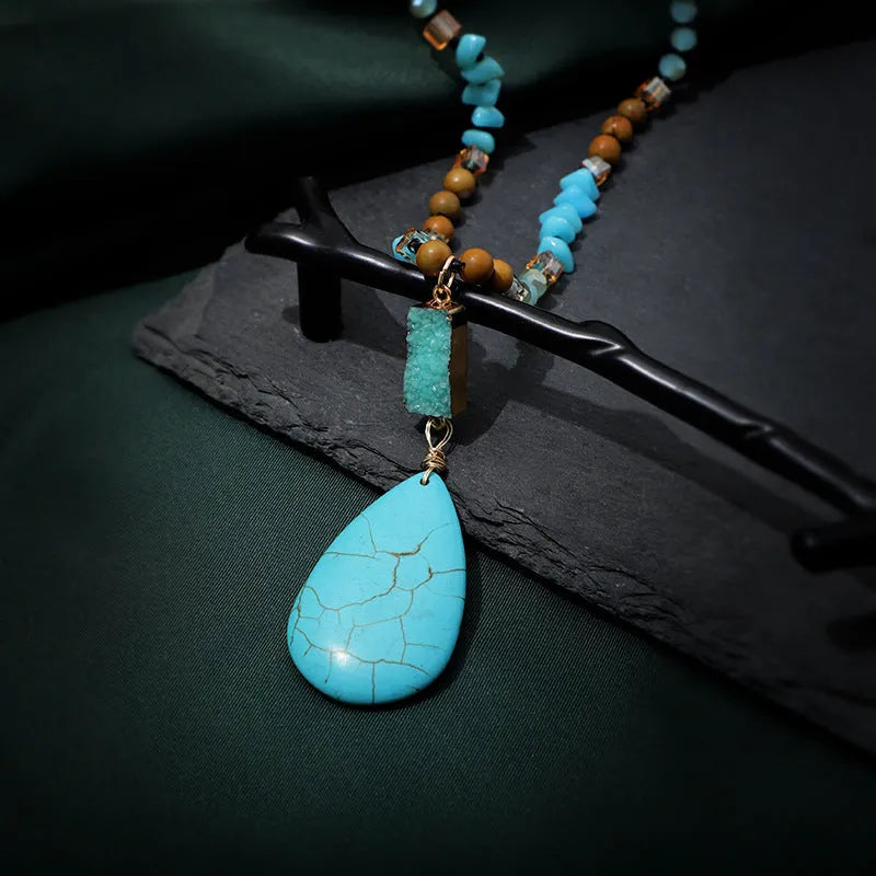 Turquoise blue large water drop pendant on a long mixed-material bead necklace.