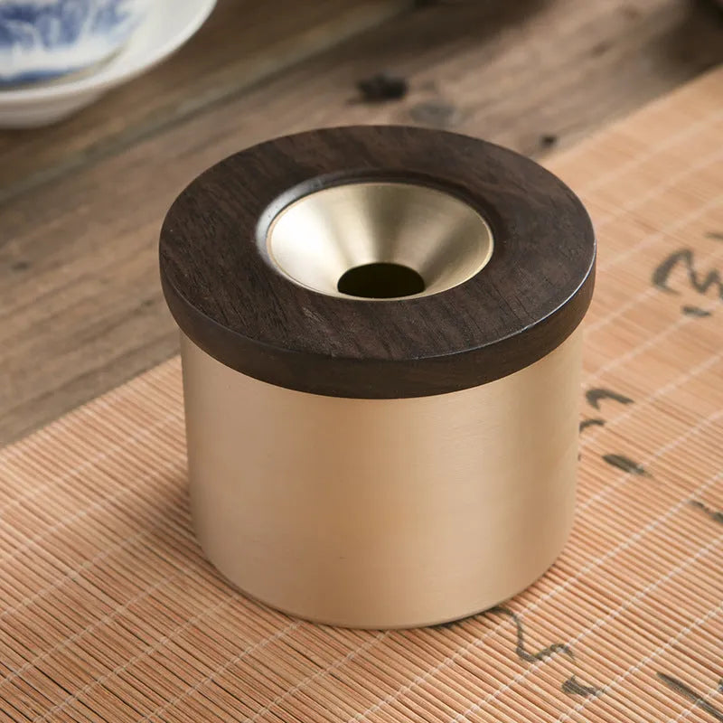 Brass ashtray with wooden lid in blackwood or rosewood finish, 6 cm diameter, on a table.