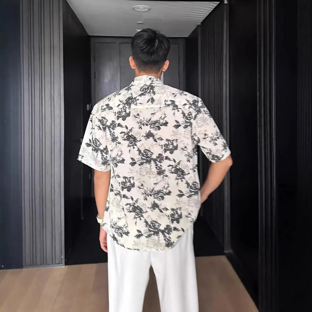 Loose black floral print short sleeve casual shirt on a hanger.