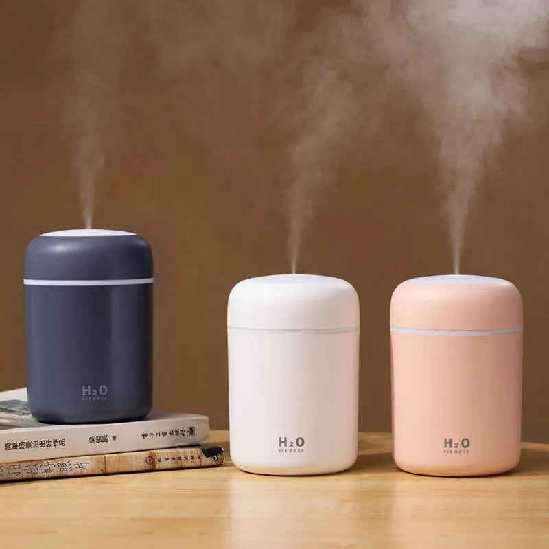 Pink USB desktop humidifier with colourful lights and 300ml water tank on wooden surface