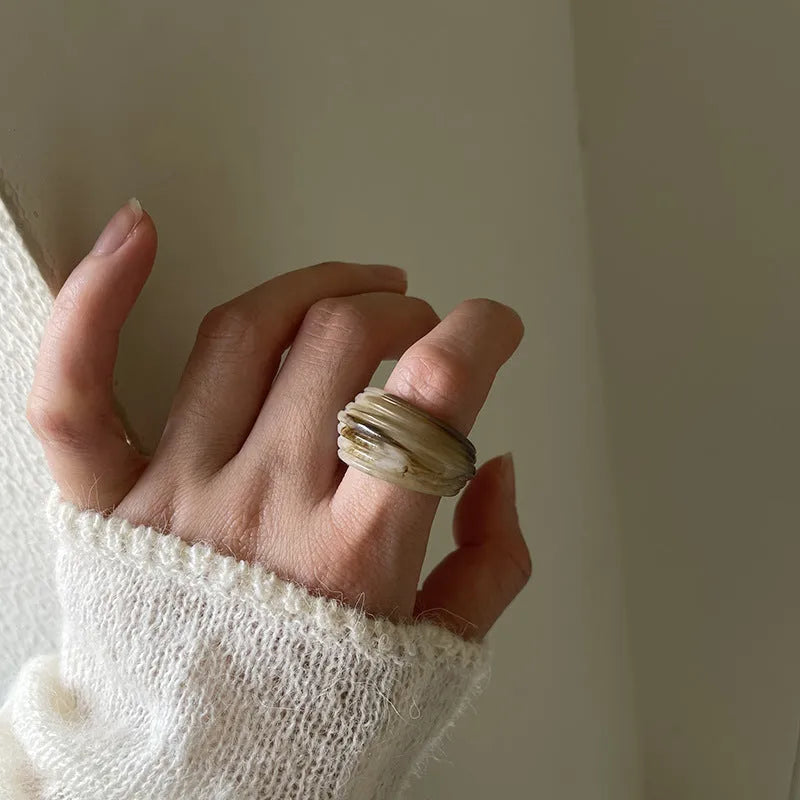 Chinese style irregular geometric wide resin ring in brown or white on a plain background.