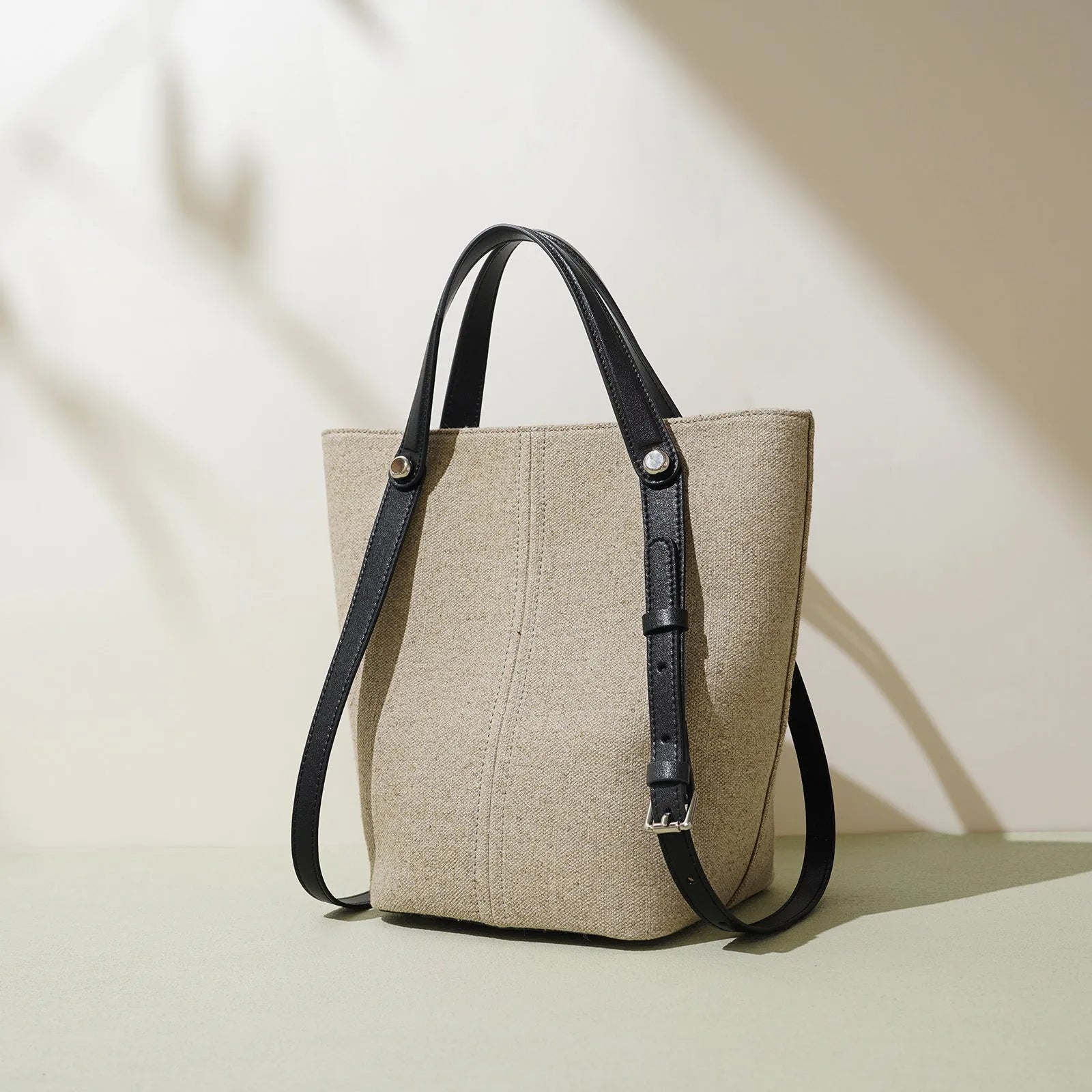 Genuine leather bucket shoulder bag in Linen Black with stitching, open outer pocket, and hand-carry strap