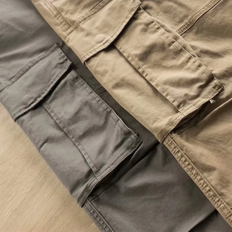 Men's solid colour cotton trousers with multiple pockets in a cropped length, shown in khaki, grey, black, and blue.