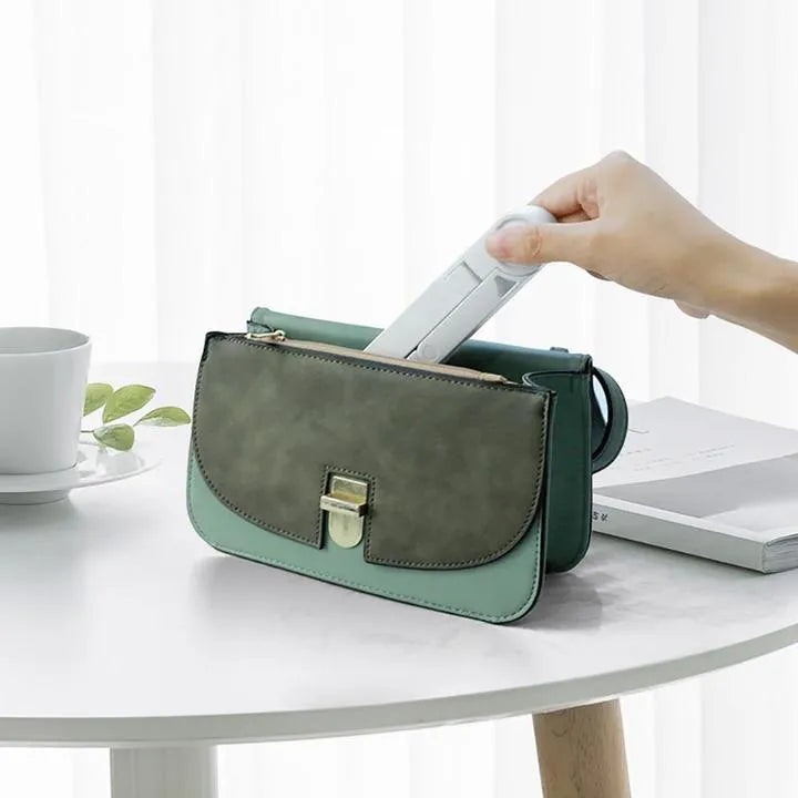 Black foldable tablet stand holding a smartphone in landscape mode on a desk, showing its compact folded size.