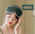 Pink portable eye spa massage goggles with USB cable on a grey background.