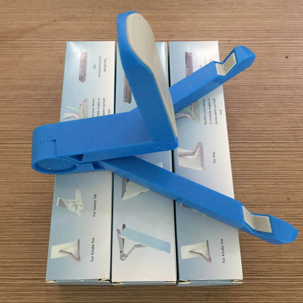 Black foldable tablet holder open in landscape mode holding a smartphone, showing its compact size and non-slip rubber surface.