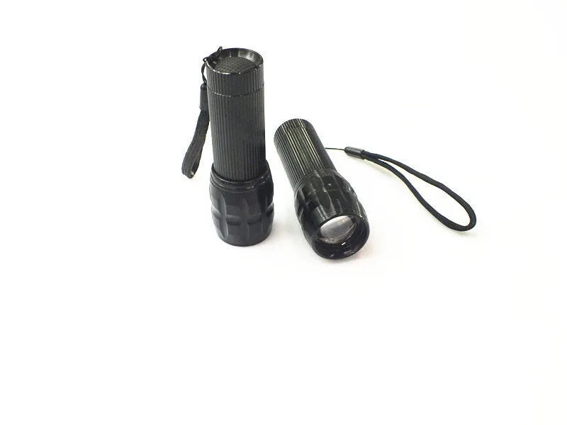 Black mini LED flashlight with telescopic head and tail push button switch on plain background