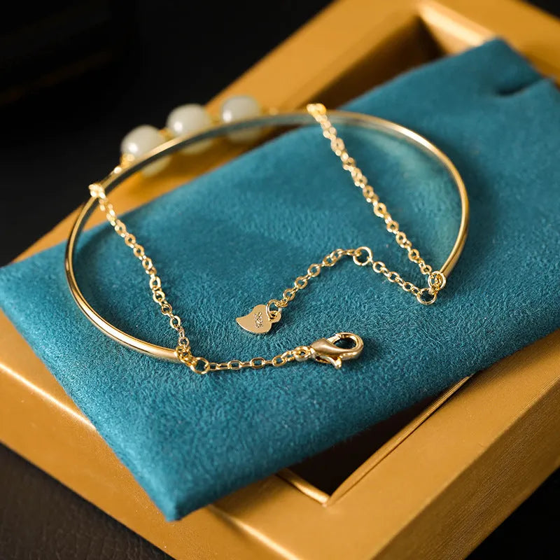 Hetian jade bracelet with gold inlay in single, double, and three bead versions on a wrist.