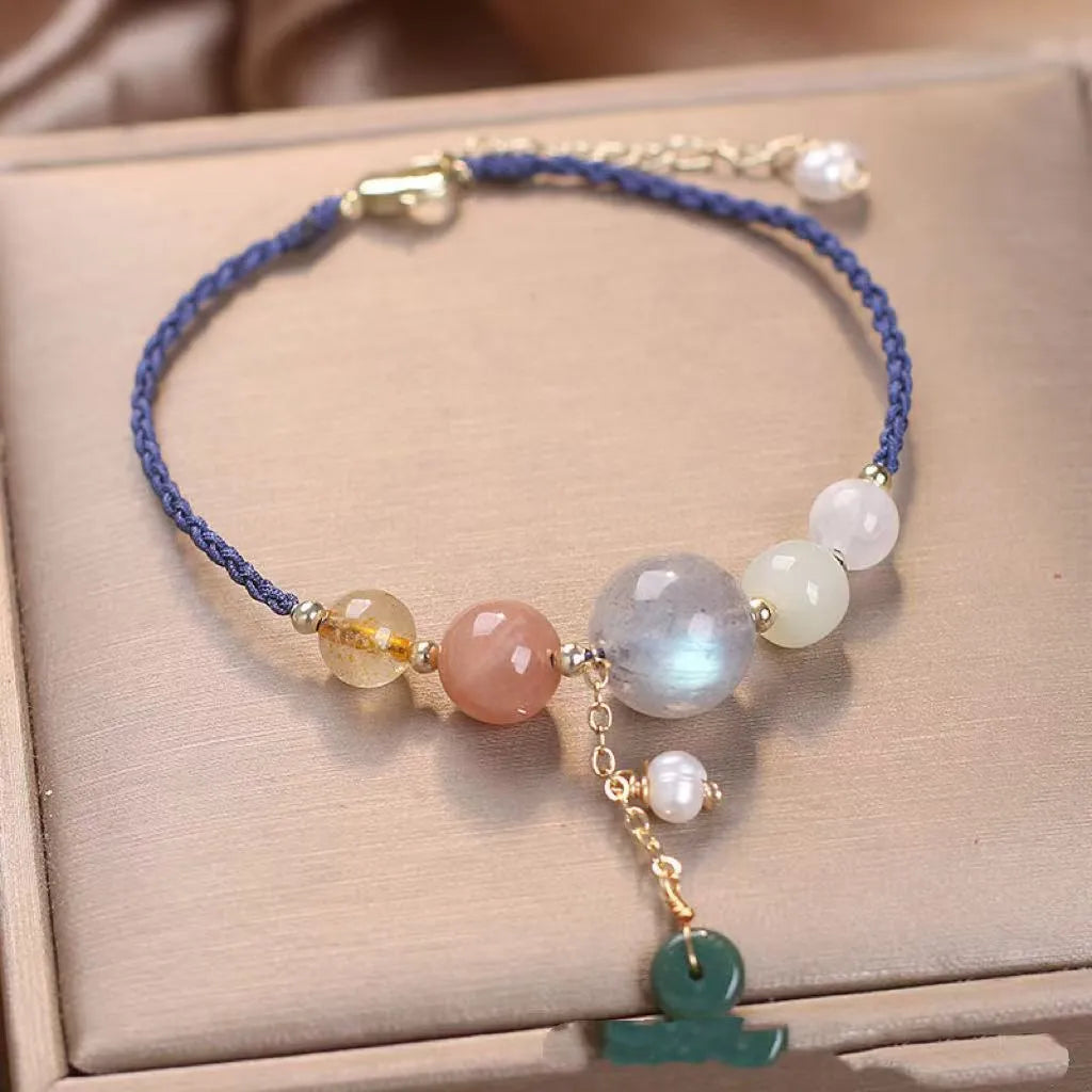 Women's hand-woven bracelet with a silver peace buckle charm and crystal sequin details on a blue band.