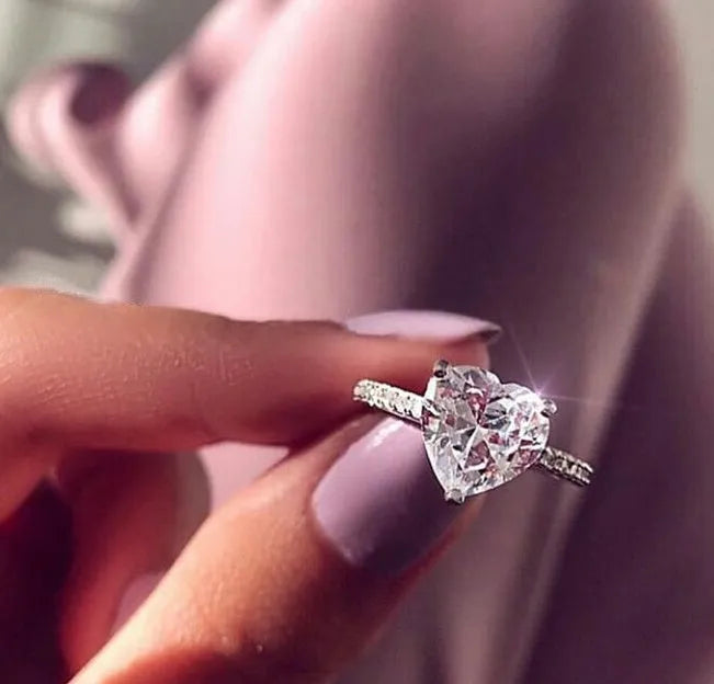 White gold alloy heart-shaped ring with AAA zircon stone on a light background