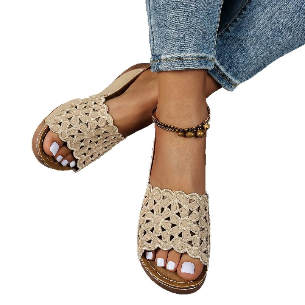 Women's black wedge beach slippers with floral cutouts on the PVC upper and a rubber sole.
