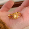 A pink crystal enamel ring with a geometric gold-plated copper band and an open mouth adjustable design.