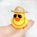 Yellow cartoon duck with straw hat car ornament on dashboard with sunglasses accessory