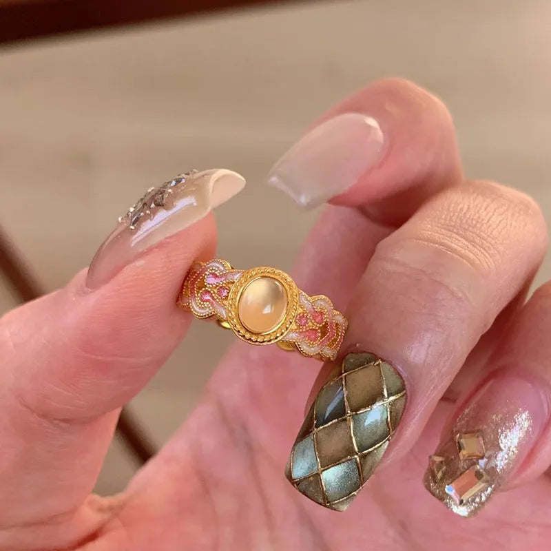 A pink crystal enamel ring with a geometric gold-plated copper band and an open mouth adjustable design.