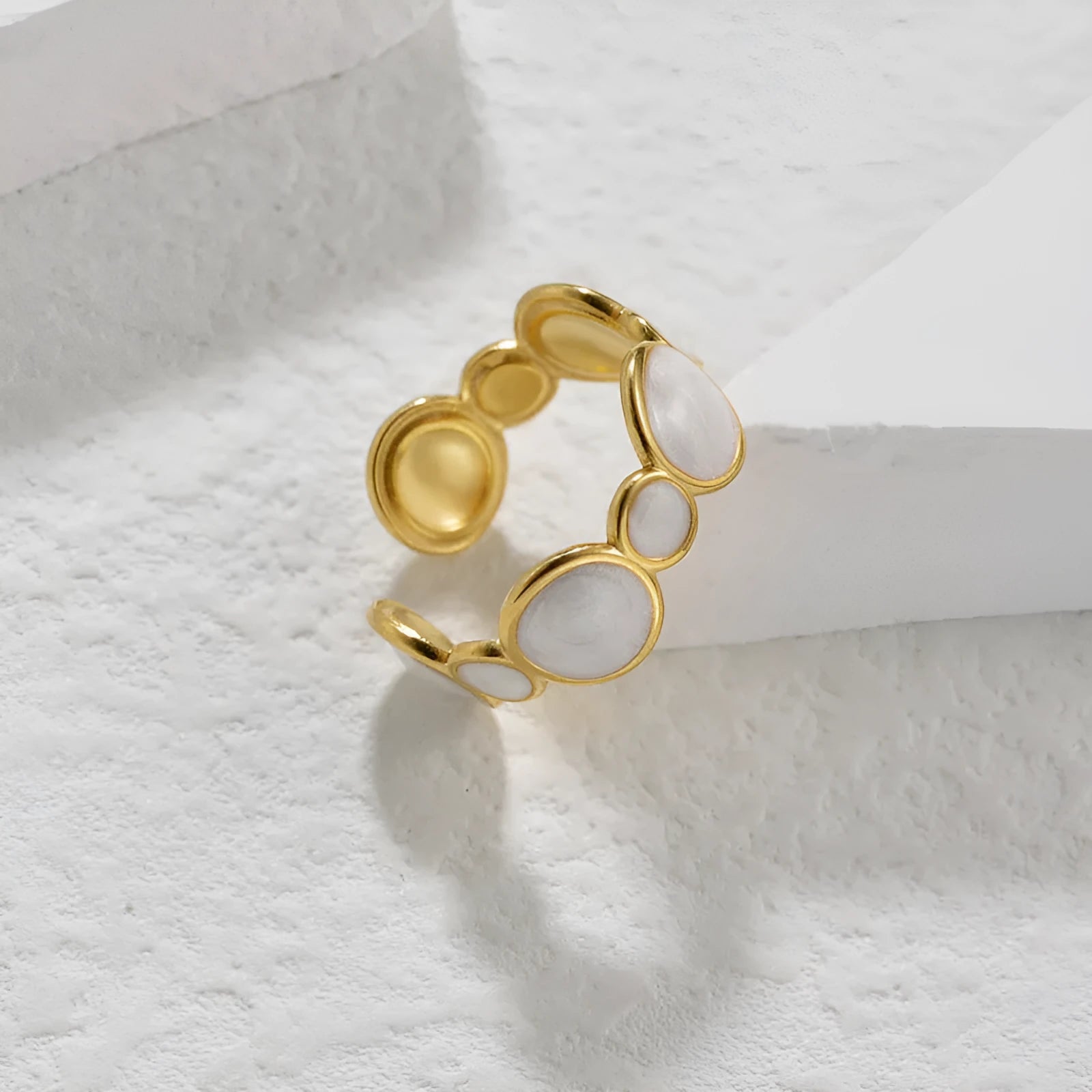 A geometric stainless steel ring with an adjustable opening on a plain background.