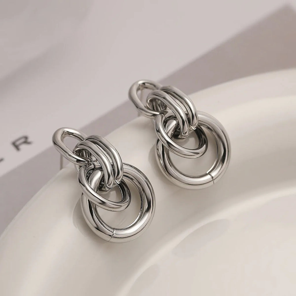 A pair of gold-coloured geometric earrings with an irregular shape on a white background.