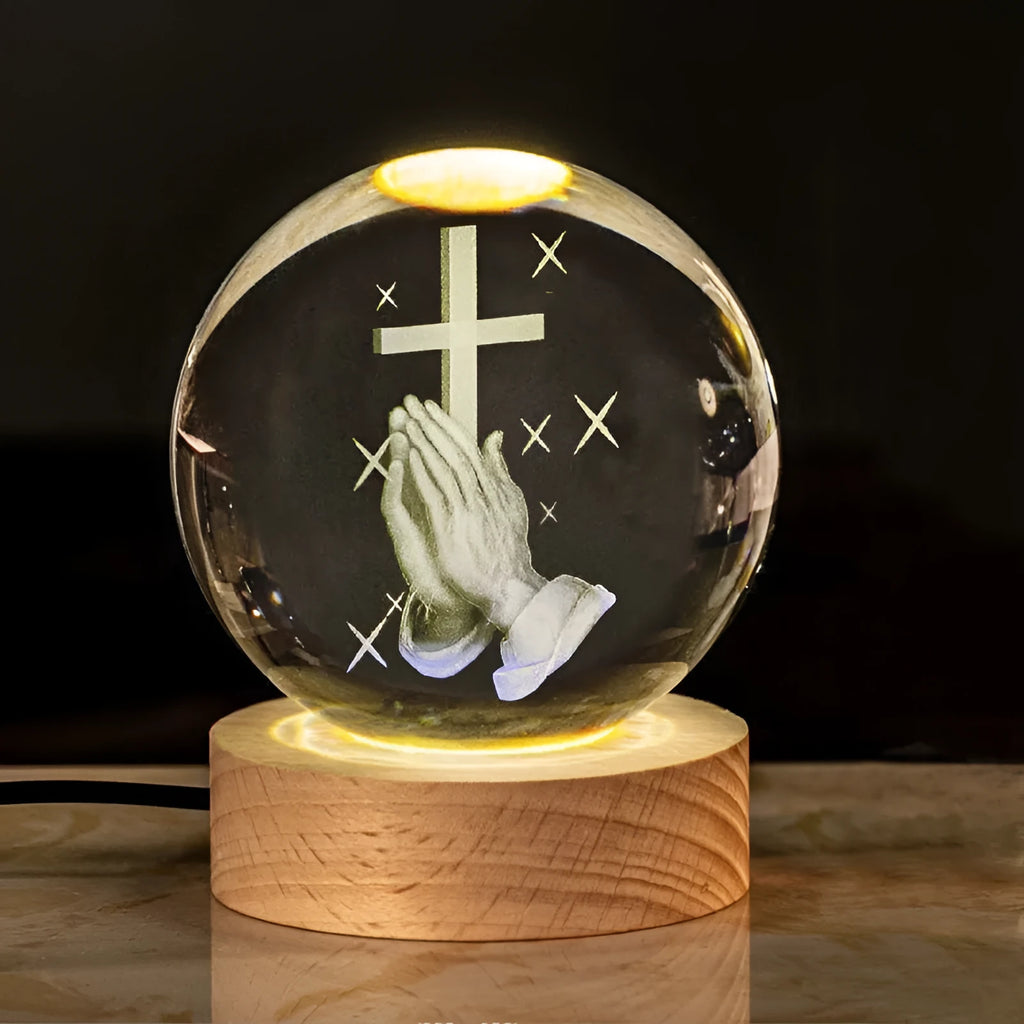 White crystal decorative ball with cross scenes on a wooden warm light base.