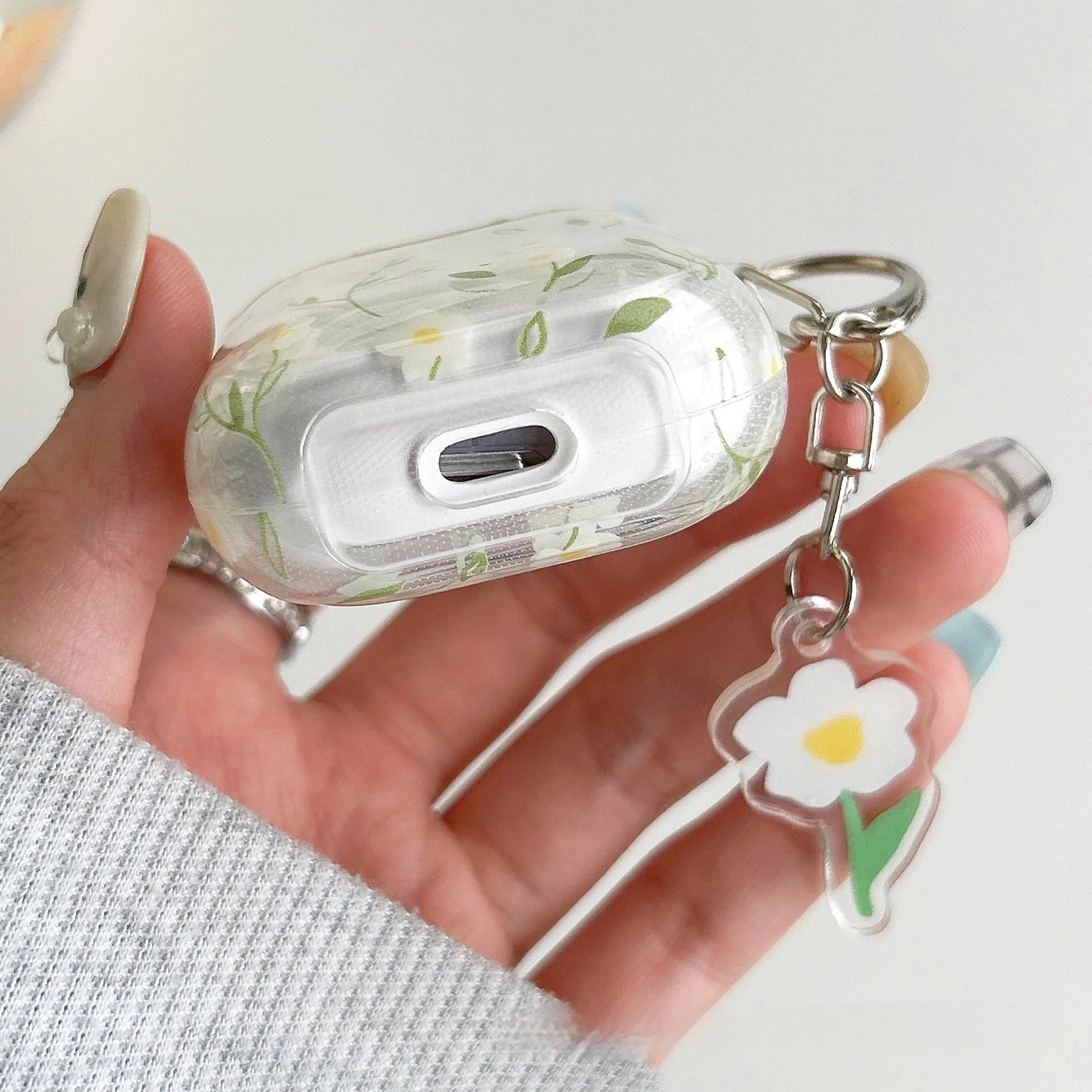 Transparent white floral TPU protective cover for Apple AirPods showing charging port access
