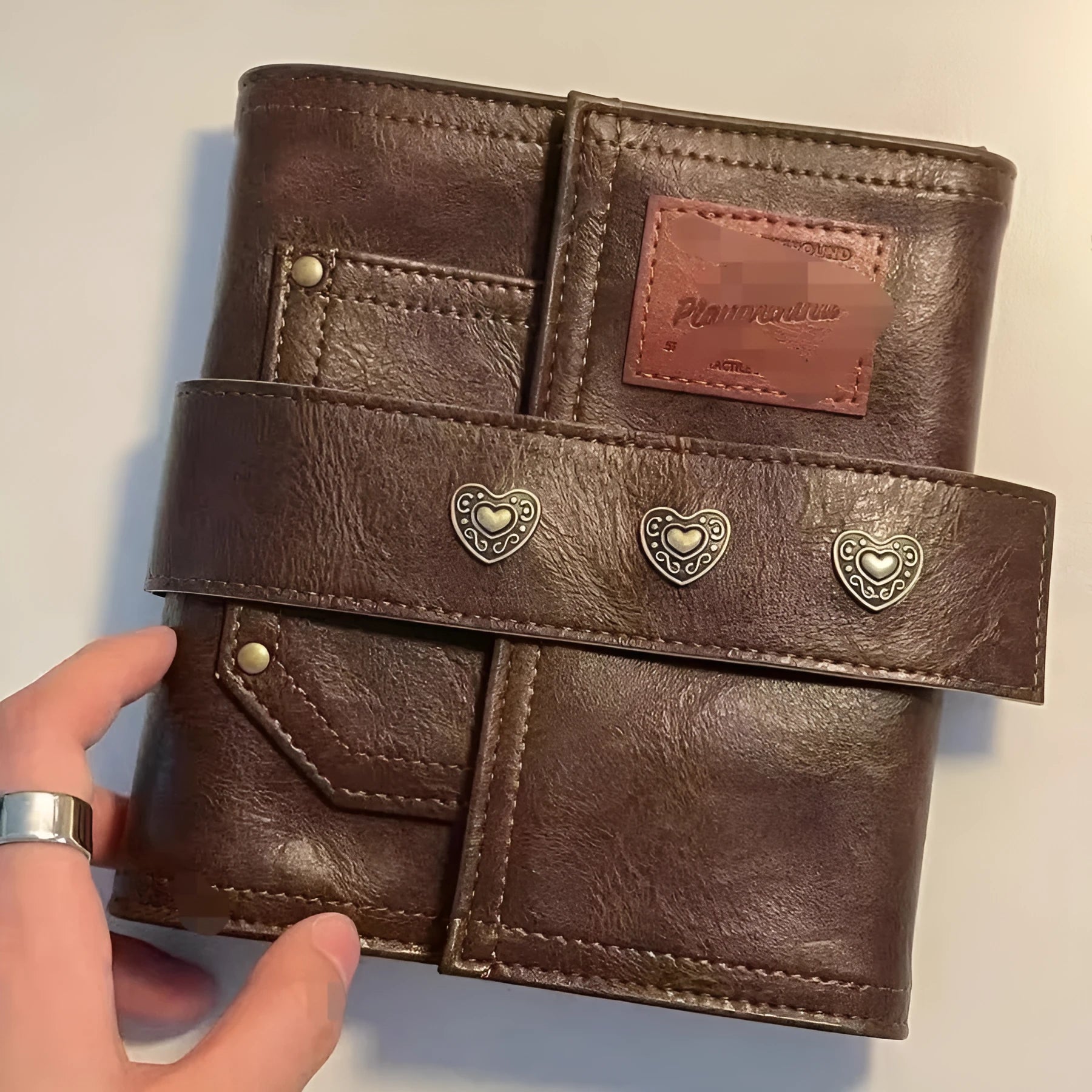 Brown A7 size notebook with a PU leather-look cover and metal buckle closure.