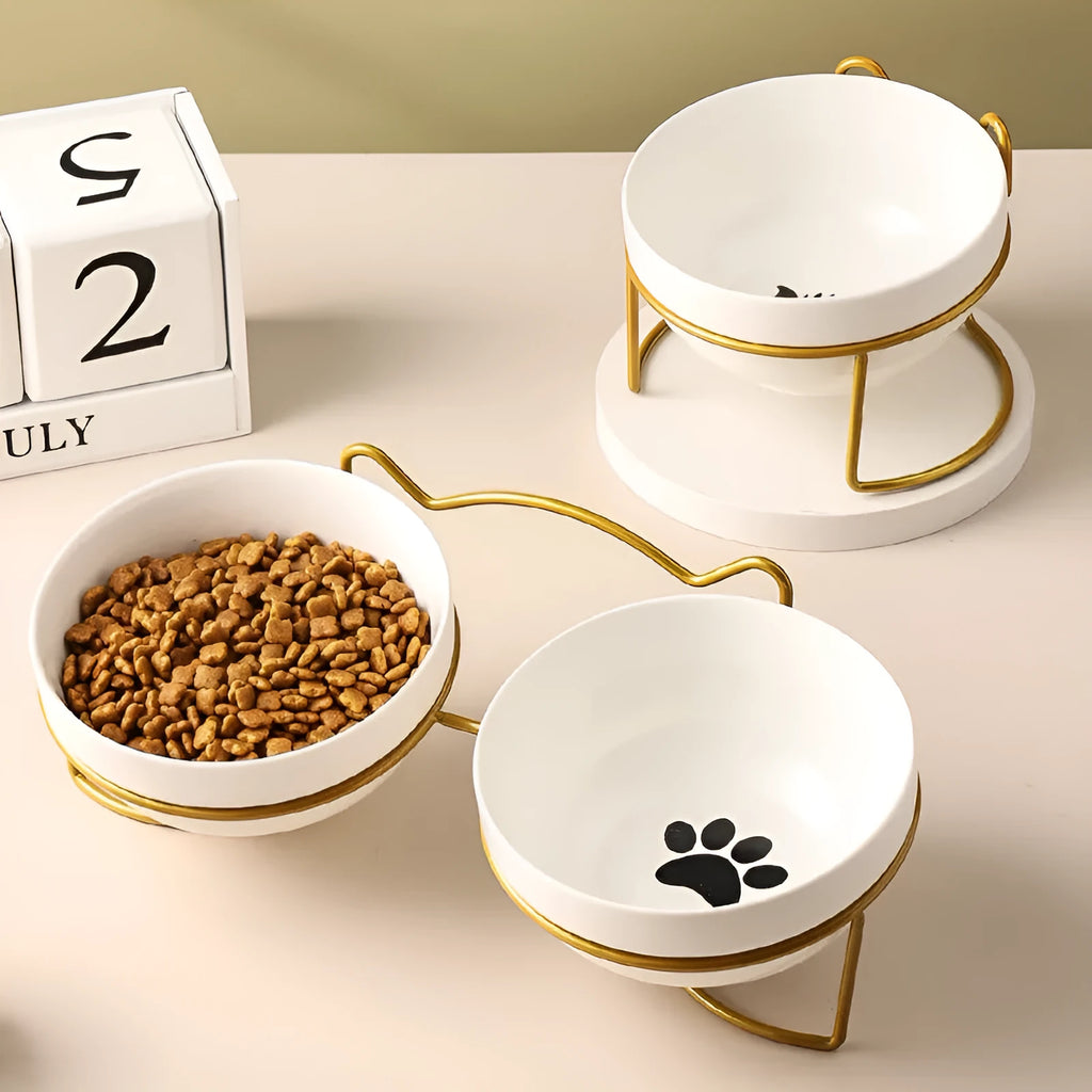 White ceramic cat bowl with cat footprints design on a black iron stand with cat-ear decoration.