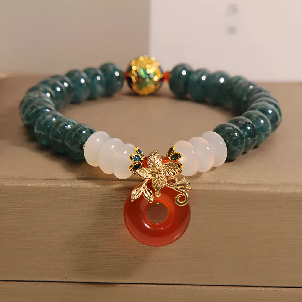 Close-up of a women's crystal bracelet with blue jade beads, red agate, and a silver peace buckle closure.