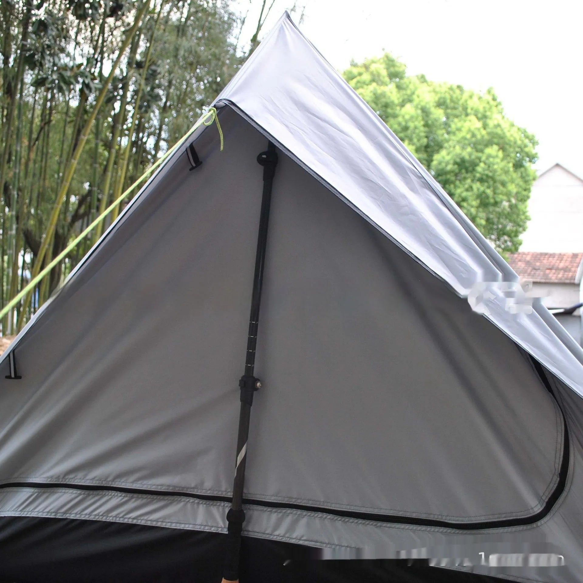 Brown A-line tent pitched with hiking poles, showing guy lines and aluminium ground nails.