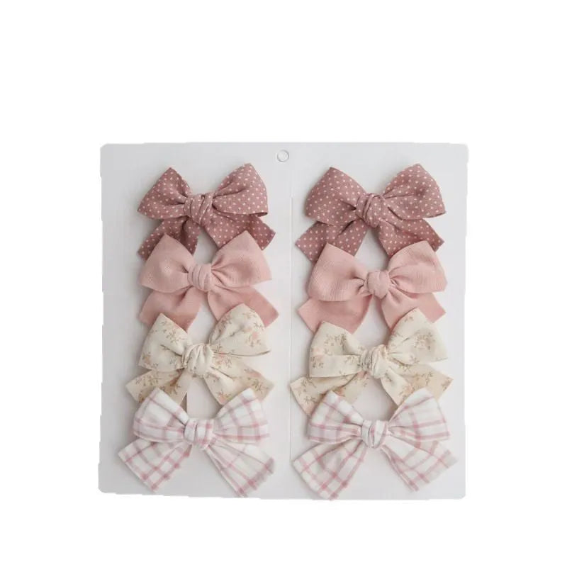 Children's cloth dovetail bow hairclip set showing eight colour pattern options