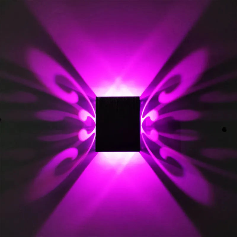 Modern aluminium butterfly-shaped LED wall lamp on a white wall with remote control.