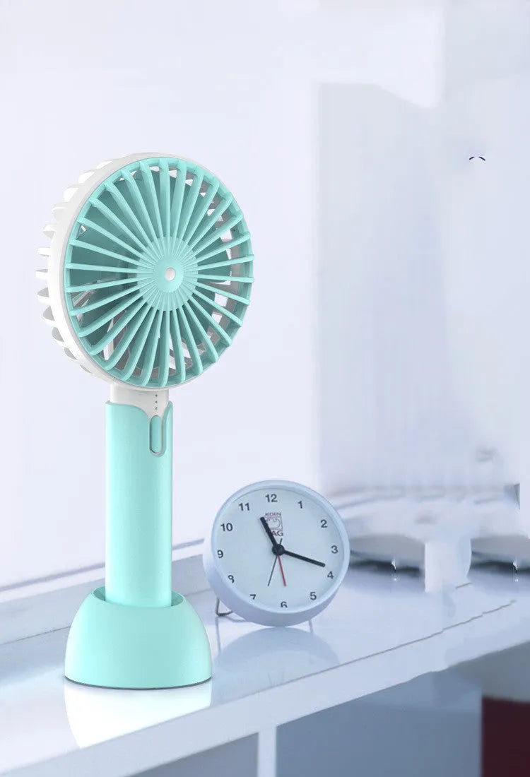 Blue handheld mini electric fan with USB cable and three-speed control on desktop