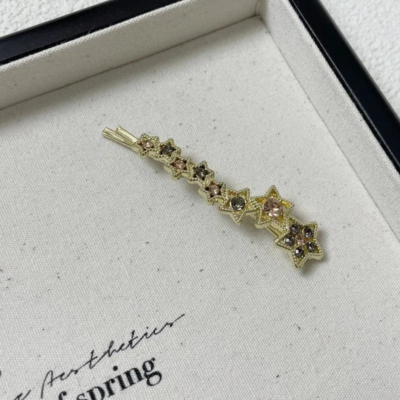 Gold-coloured Korean style hair barrette with a star and letter decoration, shown as a side clip for bangs.