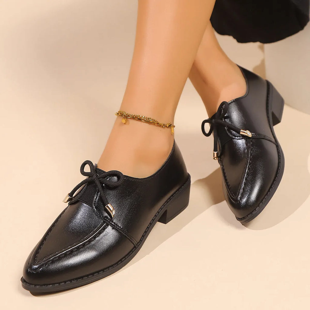Women's classic black slip-on flat shoes with a large decorative bow on the toe.