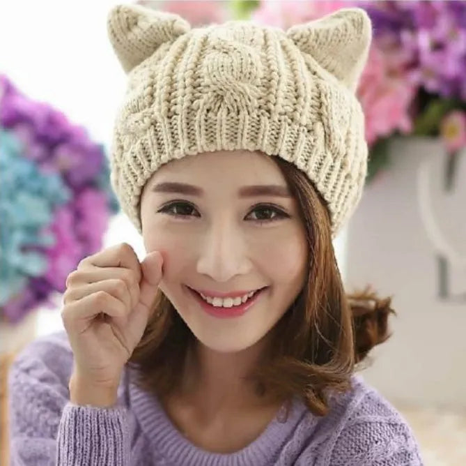 Hand-made red knitted beanie with 3D cat ears on a white background, showing side view.