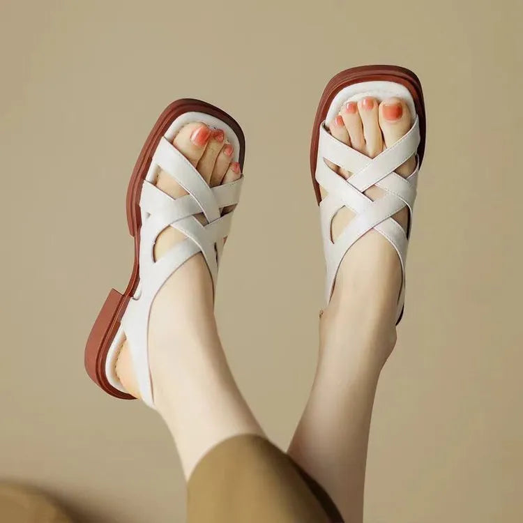 Women's glossy black patent leather sandals with square toe and cross ankle strap.