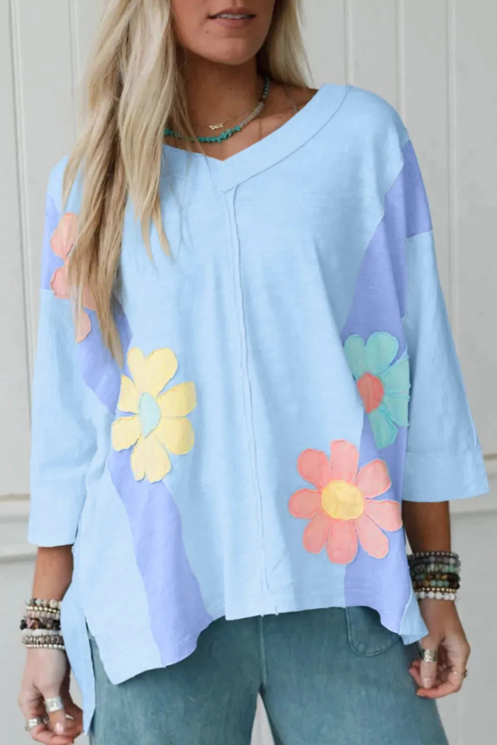 Light blue T shirt with flower patch, exposed seam bracelet sleeves, and oversized fit in sizes S M L XL