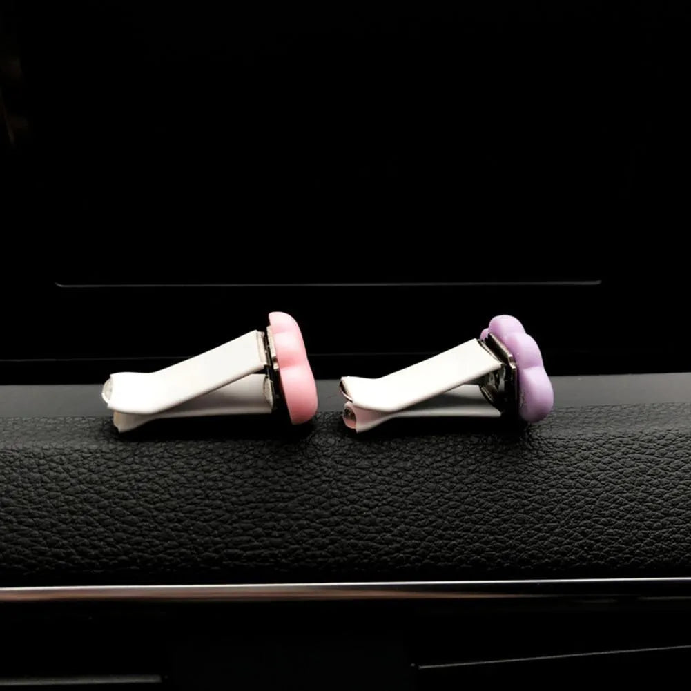 Small colourful resin car fragrance clip shown in multiple colours on a car air vent.