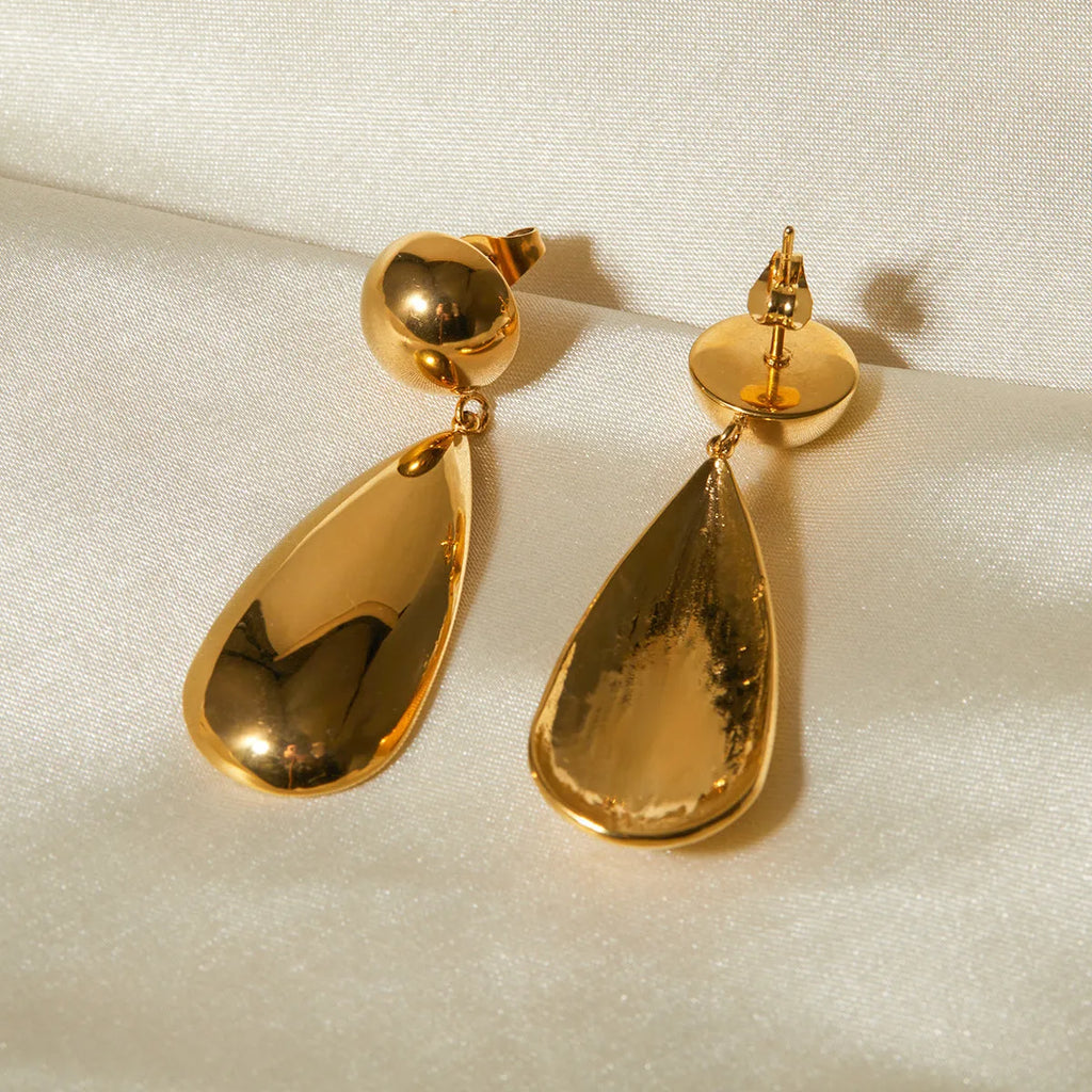 A pair of gold-coloured geometric earrings with a hemisphere base and dangling water drop pendant.