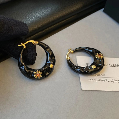 A pair of retro alloy ear studs with a dripping oil finish and black rhinestone detail.