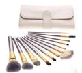 Persian makeup brush set with rice white bristles and champagne coloured handles laid out in rows.
