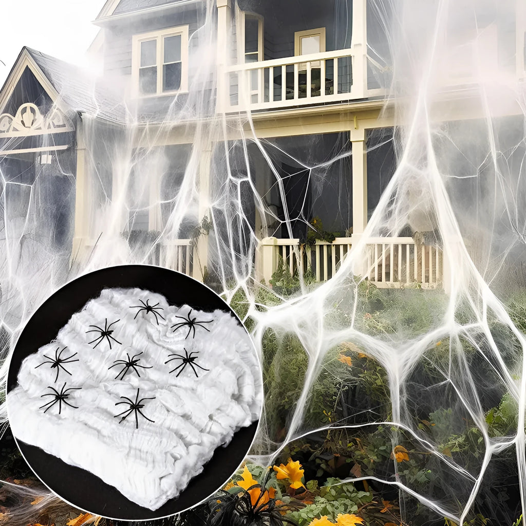 White cotton spider web Halloween decoration with plastic spiders draped over a surface.